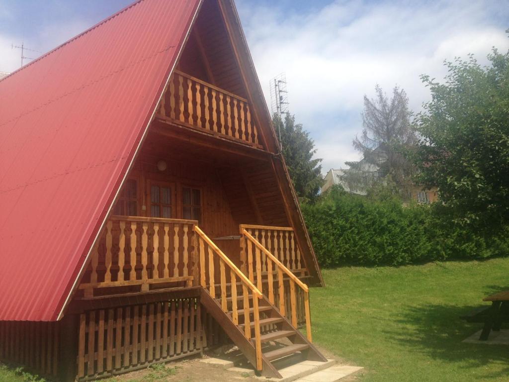 eine Blockhütte mit einem roten Dach und einer Holztreppe in der Unterkunft "Domek na Wiejskiej 4" Polańczyk , 696-025-331 in Polańczyk