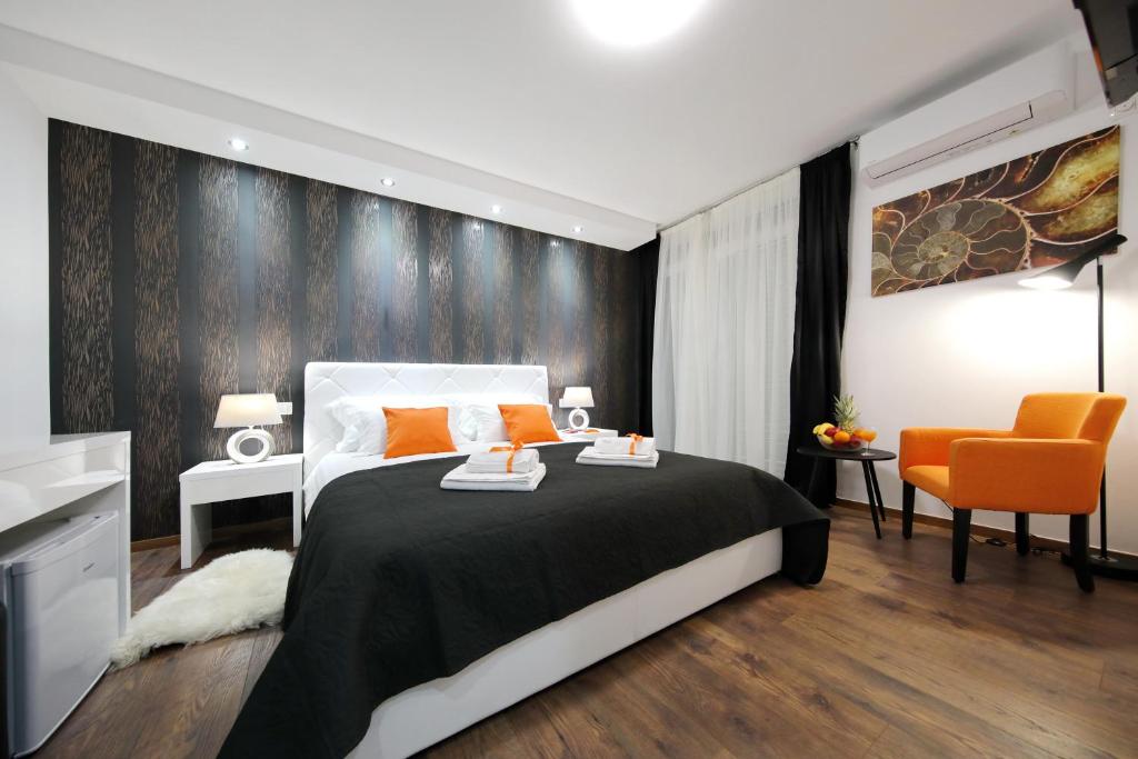 ザダルにあるZadar Luxury Roomsのベッドルーム(黒と白のベッド1台、オレンジの椅子付)