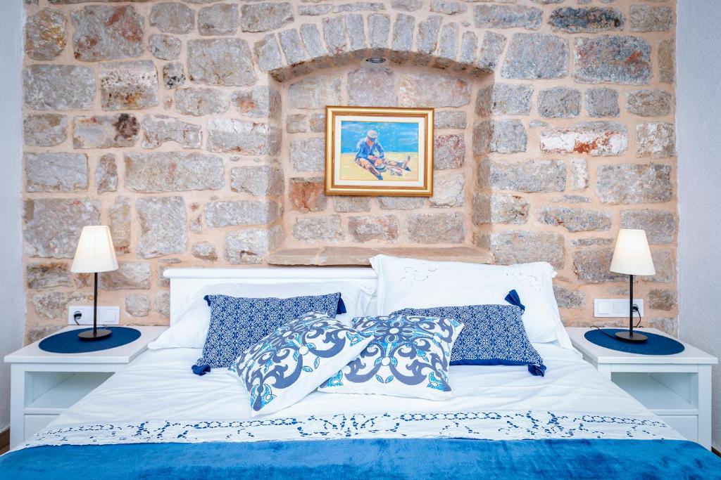 a bedroom with a white bed and a stone wall at Villa Riva in Jelsa