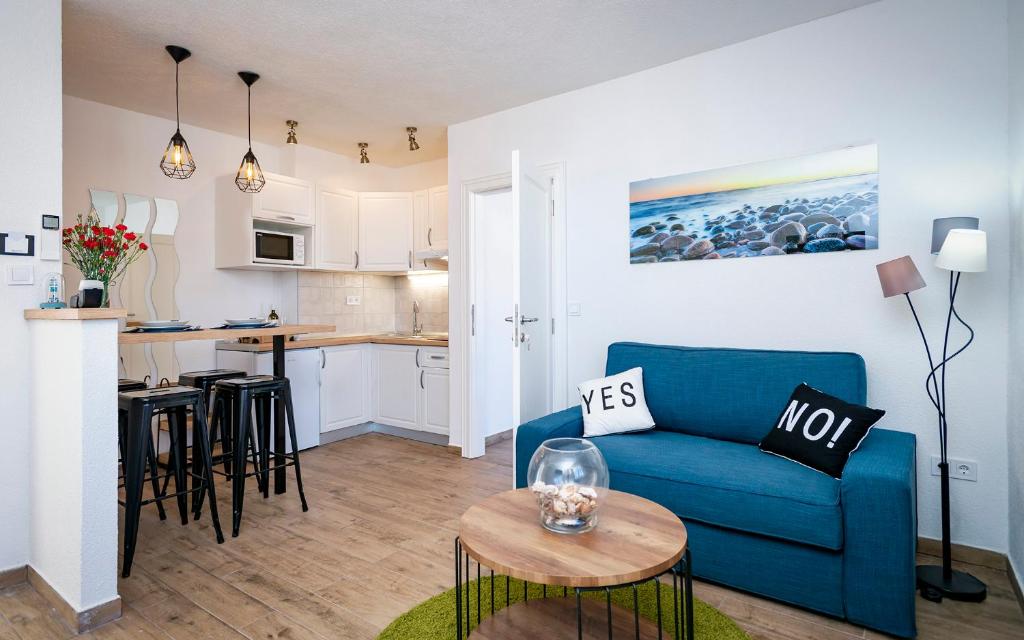 a living room with a blue couch and a kitchen at Villa Riva in Jelsa