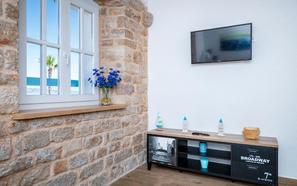 a living room with a tv and a brick wall at Villa Riva in Jelsa