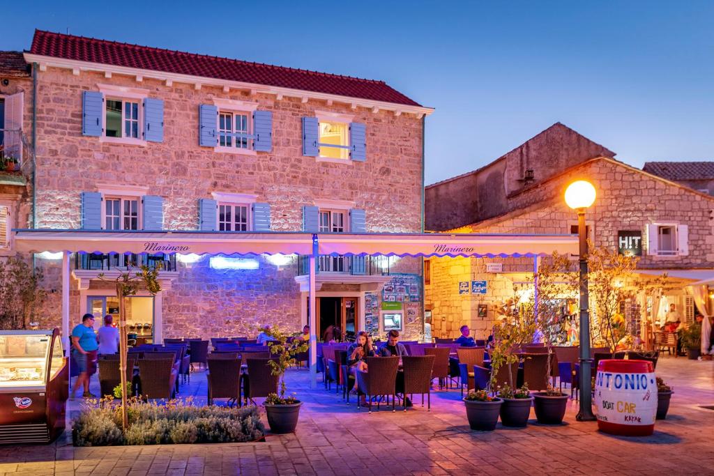 a group of people sitting at tables outside of a building at Villa Riva in Jelsa