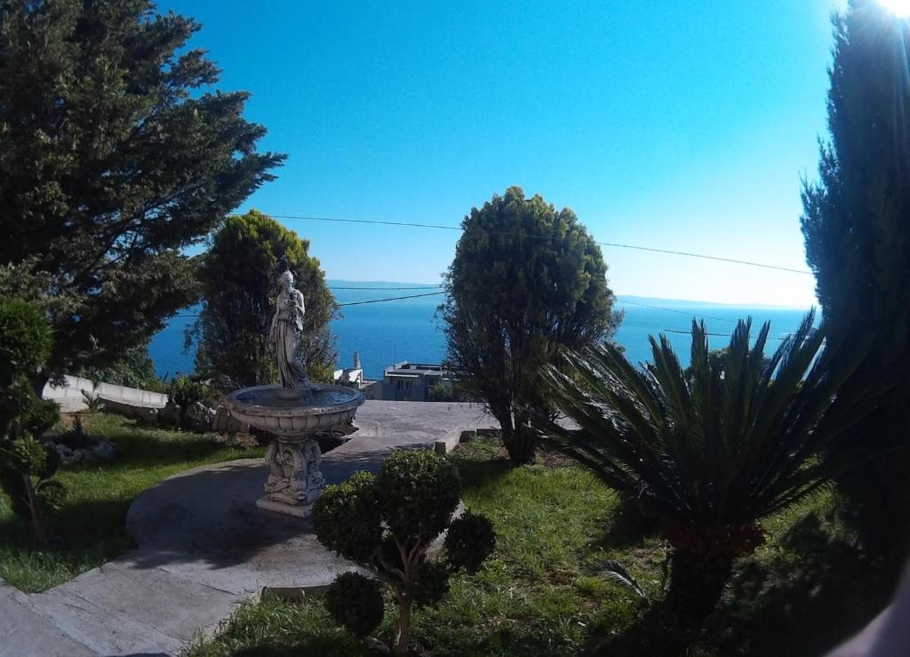 a statue in a garden with the ocean in the background at Apartman Horizont in Omi&scaron;