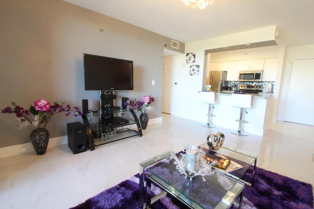 a living room with a tv and a glass table at Yacht Club at Aventura 1 Bd 1 Bth Brand New in Aventura