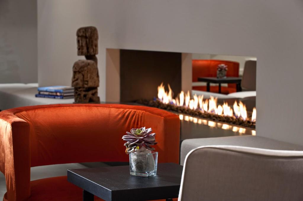 a room with a fireplace with a orange chair and a table at Wyndham Stuttgart Airport Messe in Stuttgart