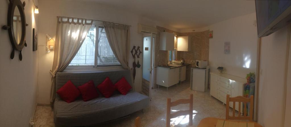 sypialnia z łóżkiem z czerwonymi poduszkami oraz kuchnia w obiekcie Apartamentos Villa Mar 13 Torremolinos w mieście Torremolinos