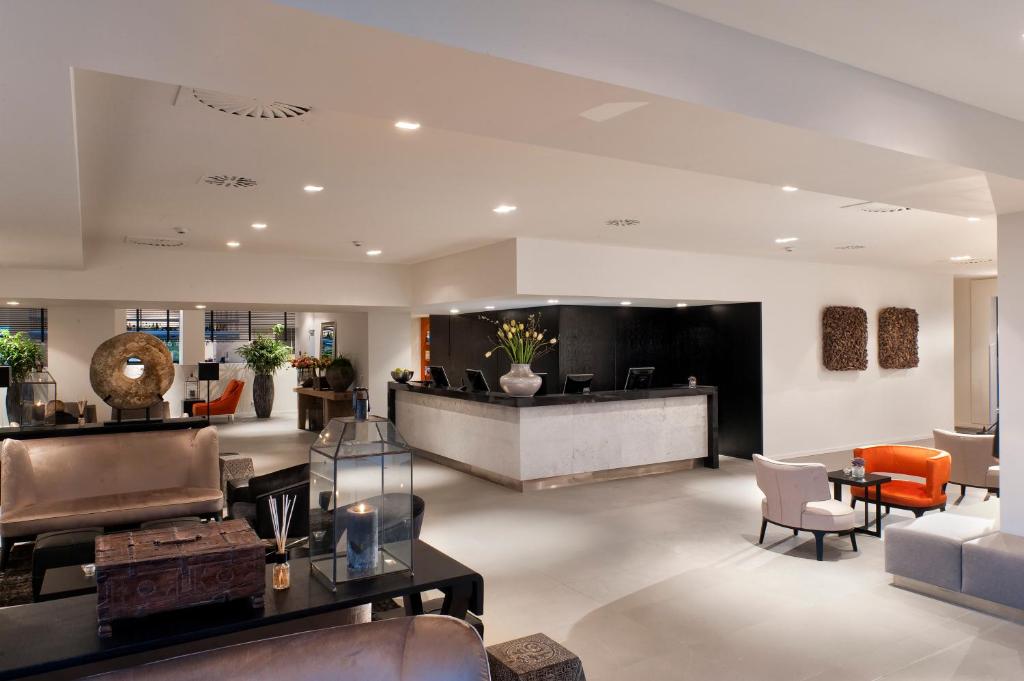 a lobby with a waiting area with chairs and tables at Wyndham Stuttgart Airport Messe in Stuttgart
