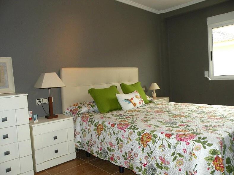 um quarto com uma cama grande e almofadas verdes em Apartamento em El Perelló