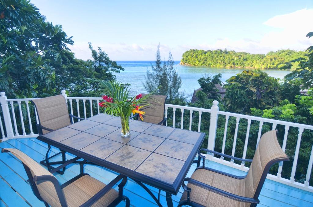 a table and chairs on a balcony with a view of the ocean at Moon San Villa at the Blue Lagoon in Port Antonio