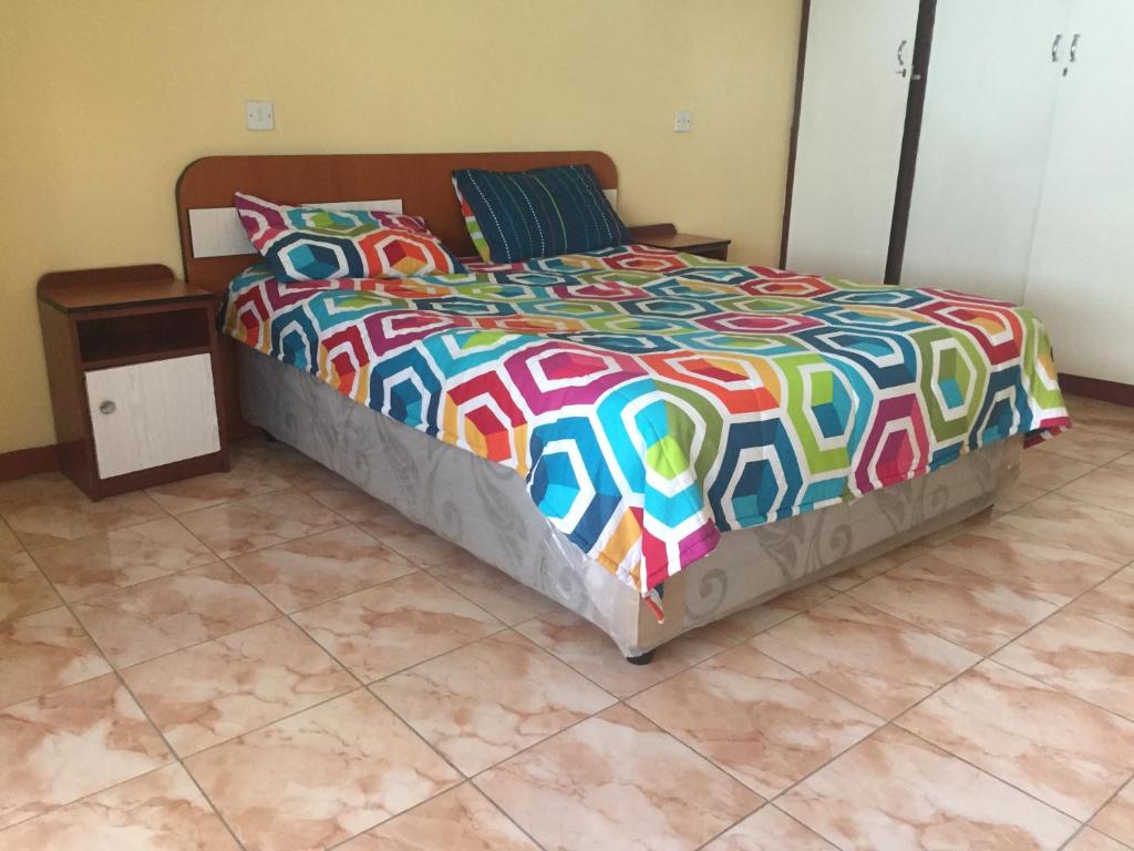 a bed with a colorful comforter in a bedroom at Maoni Guest House in Blantyre