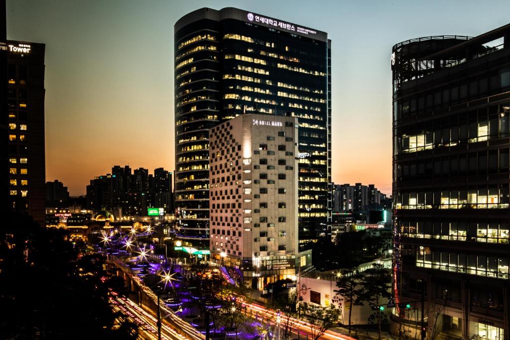 eine Skyline der Stadt in der Nacht mit einem hohen Gebäude in der Unterkunft Hotel Manu Seoul in Seoul