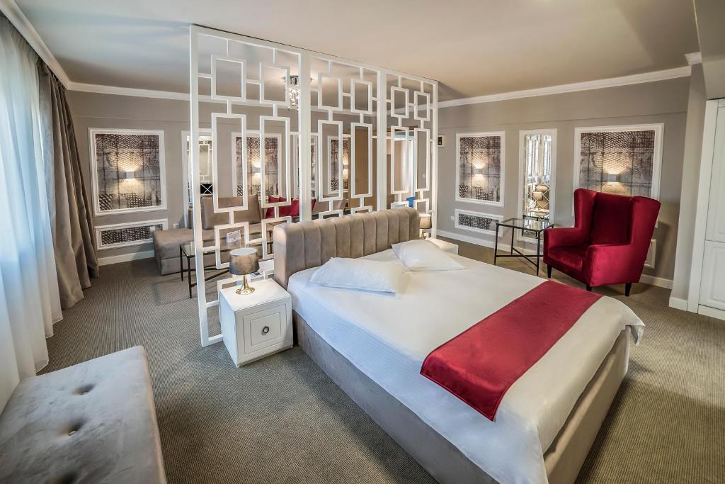 a bedroom with a large bed and a red chair at Hotel Boavista in Timişoara