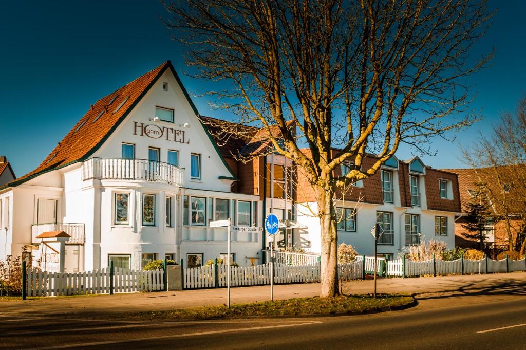 ブクステフーデにあるHotel an der Linah garniの白いホテルの前に木が立ち並ぶ