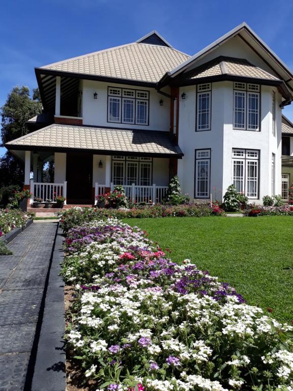 a house with flowers in the front yard at The Hill Town Cottage in Nuwara Eliya