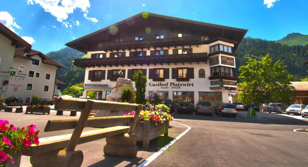 ein Gebäude an der Seite einer Straße mit einer Bank in der Unterkunft Hotel Restaurant Platzwirt in Rauris