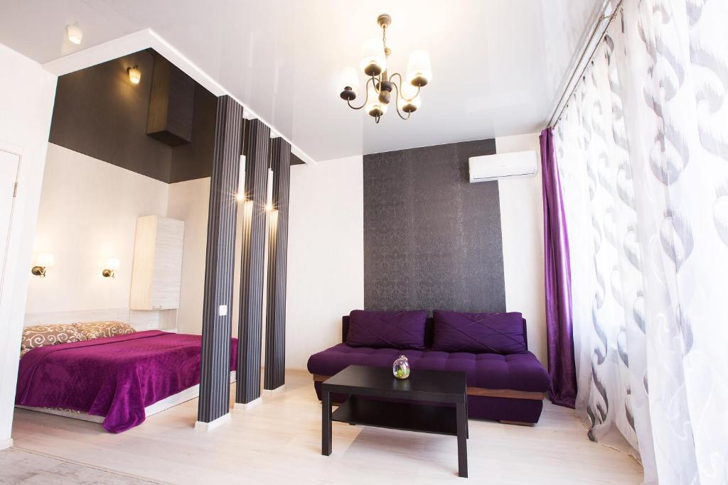 شقق سومسكايا الفندقية في خاركوف: غرفة معيشة مع أريكة أرجوانية وسرير