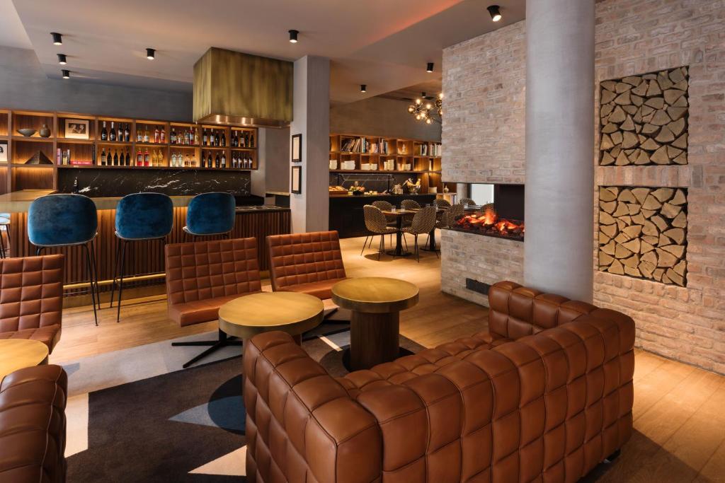 a bar with leather furniture and a fireplace at Hotel Scheuble in Zürich