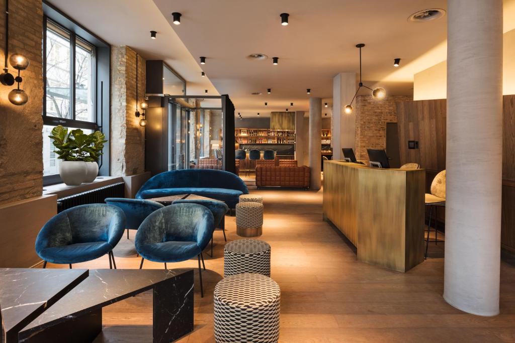 a lobby of a hotel with blue chairs and tables at Hotel Scheuble in Zürich