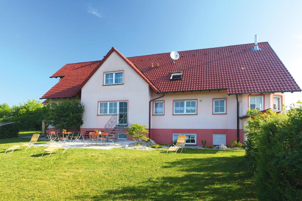 una casa con un tetto rosso su un cortile di Pension Oppelt a Rauhenebrach