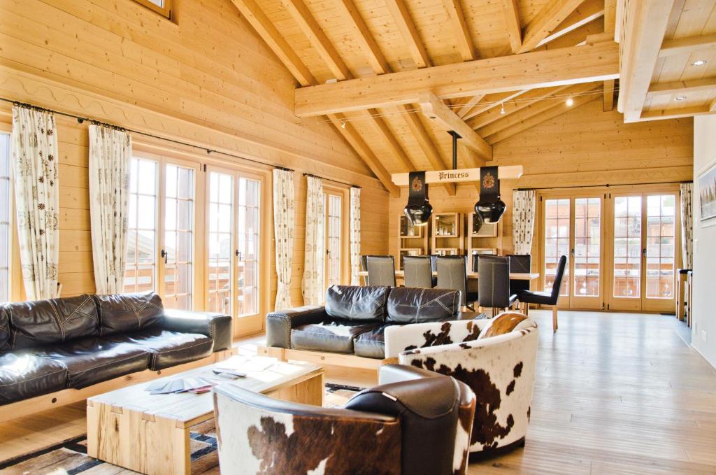 a living room with leather furniture and wooden ceilings at Chalet Princess - GRIWA RENT AG in Grindelwald