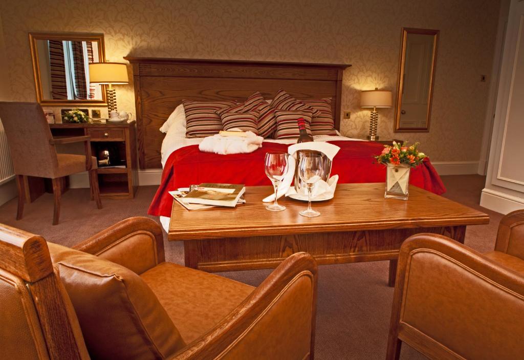 Habitación de hotel con cama y mesa con copas de vino en Grinkle Park Hotel en Loftus