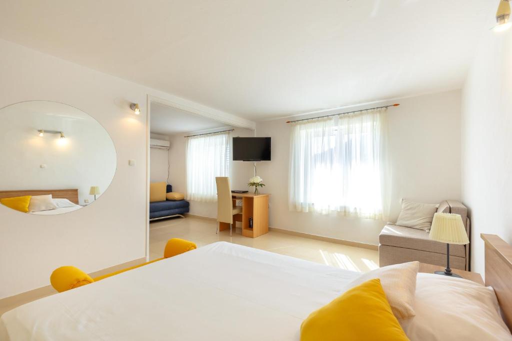 a white bedroom with a bed and a mirror at Villa Misita in Dubrovnik