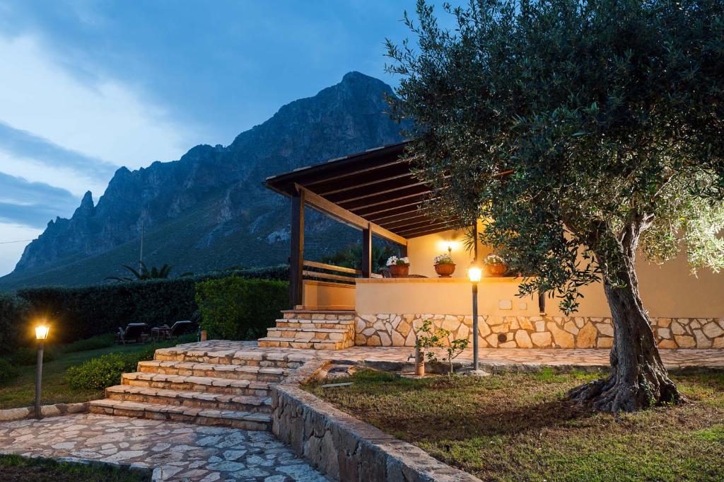una casa con escaleras y un árbol con montañas en el fondo en Villa Baia Verde, en Custonaci