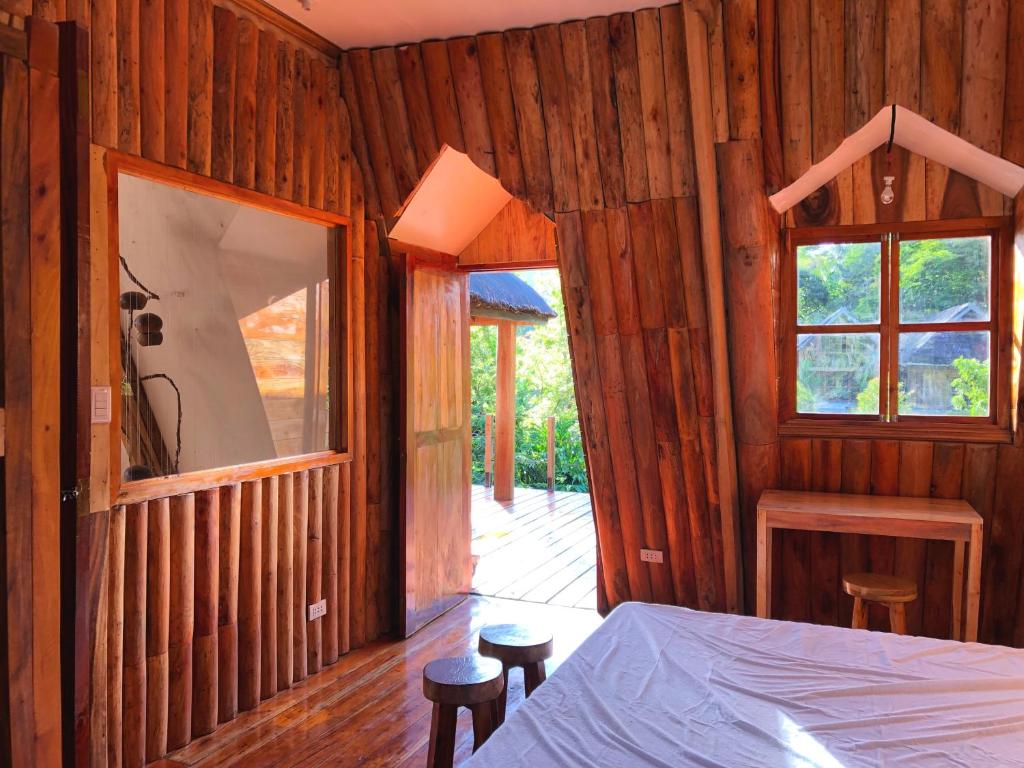 una camera da letto con pareti in legno, un letto e una finestra di Camiguin Volcano Houses - A-Frame house a Mambajao