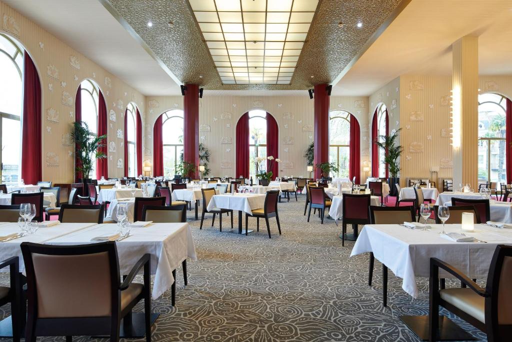 a dining room with white tables and chairs at Hotel &amp; Spa Vacances Bleues Le Splendid in Dax