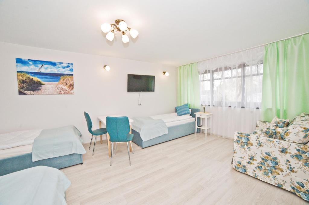 ソポトにあるLa Playa by Grand Apartmentsのベッド2台、テーブル、ソファが備わる客室です。