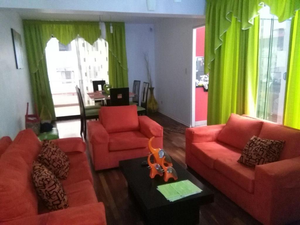 una sala de estar con sofás rojos y cortinas verdes en Mi casa es su casa, en Lima