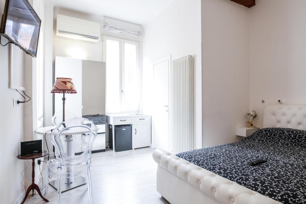 a white bedroom with a bed and a chair at Myrtha bb in Bologna