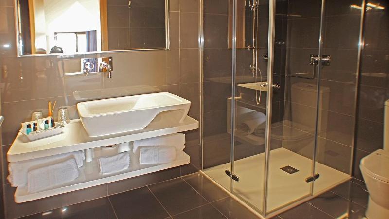 uma casa de banho com uma cabina de duche em vidro e um lavatrio. em OHStudios em Oliveira do Hospital