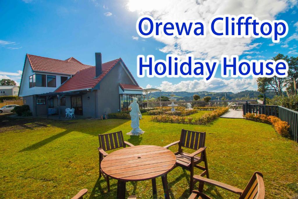 una mesa y sillas en un patio con una casa en Orewa Cliff Top, en Orewa