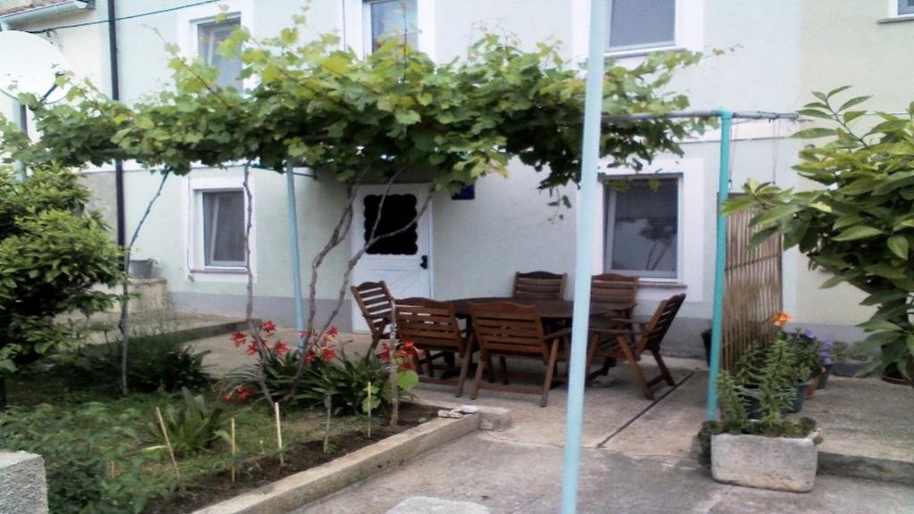 a garden with a wooden table and chairs in front of a house at Holiday House Klevini Dvori in Olib