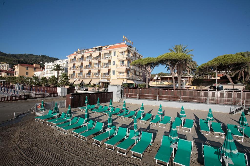 B&B HOTEL Diano Marina Palace في ديانو مارينا: صف من الكراسي الخضراء ومبنى