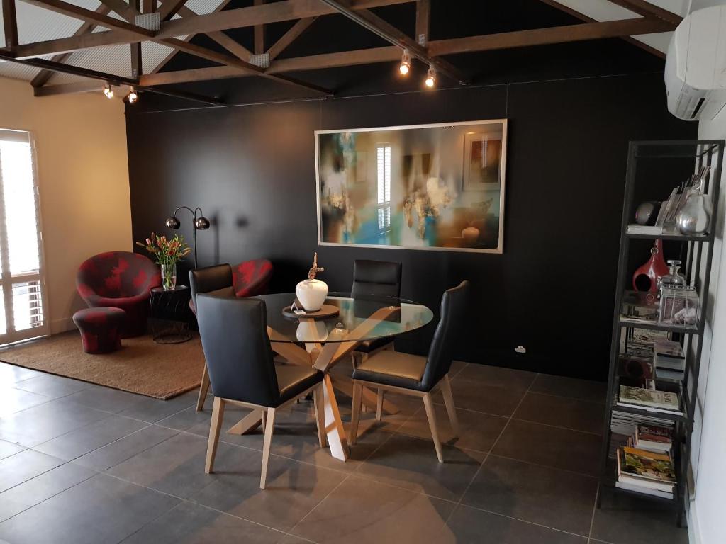 a dining room with a glass table and chairs at Irongate Studio B&B in Mintaro