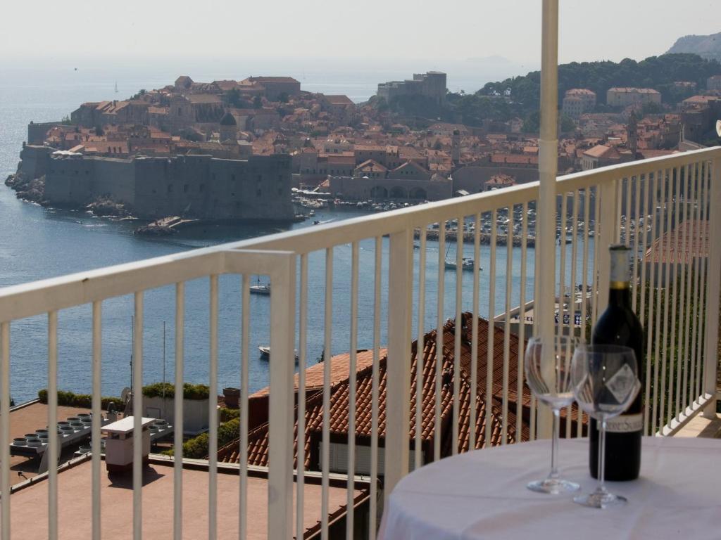 a table with a glass of wine on a balcony at Sipa Apartments in Dubrovnik