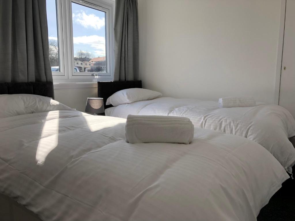 three white beds in a room with a window at Glenrothes Central Apartments - One bedroom Apartment in Glenrothes