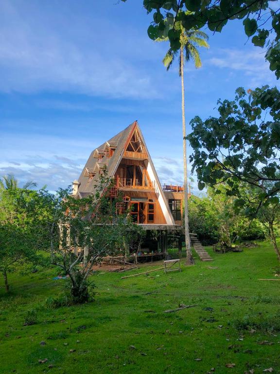 una casa in un campo con un albero di Camiguin Volcano Houses - A-Frame house a Mambajao