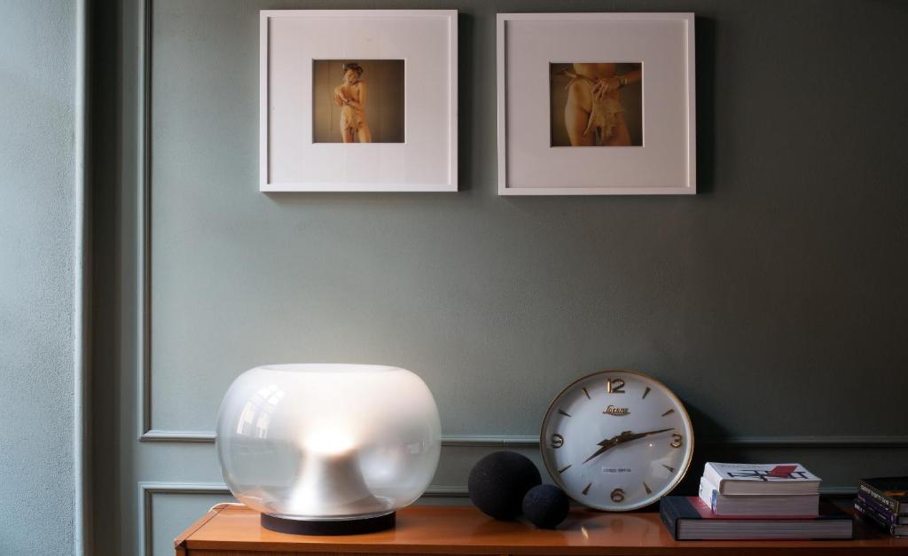 a table with a clock and pictures on the wall at Suites Menaggio in Menaggio