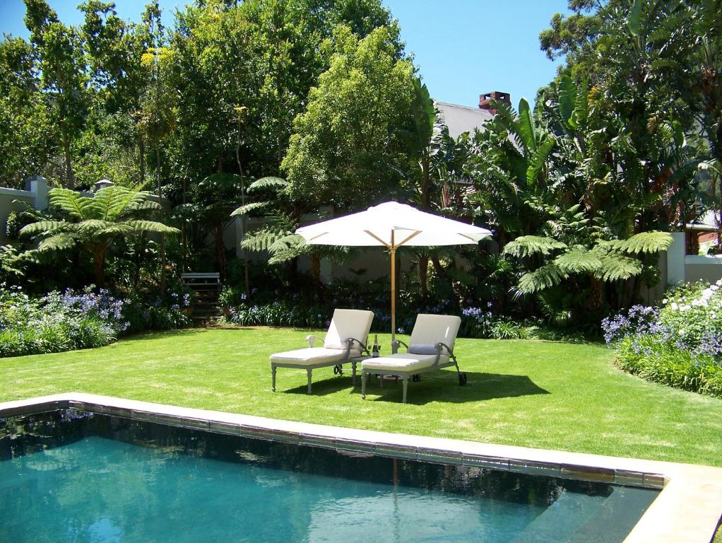 2 sillas y sombrilla junto a la piscina en Forest Rest en Somerset West