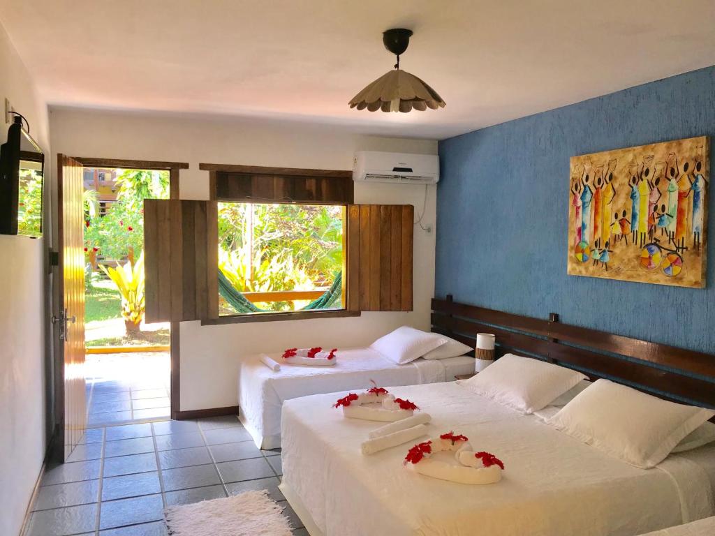 a bedroom with two beds with red flowers on them at Hotel Pousada Marambaia in Arraial d'Ajuda