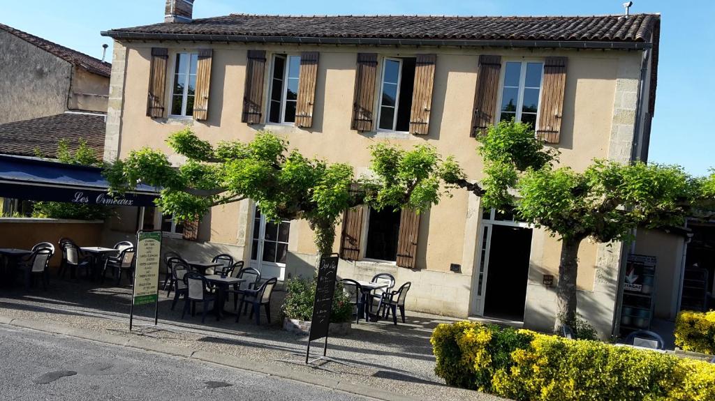 a building with tables and chairs in front of it at les Ormeaux in Sauternes
