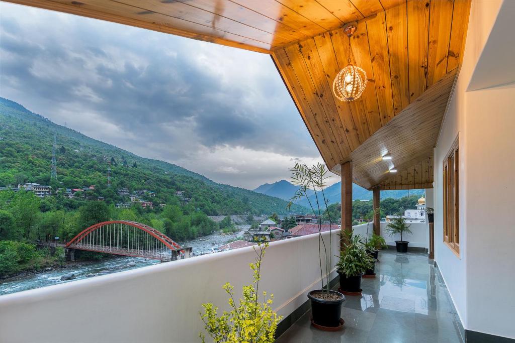 einen Balkon mit Blick auf einen Fluss und eine Brücke in der Unterkunft Hotel Kullu Valley in Kulu