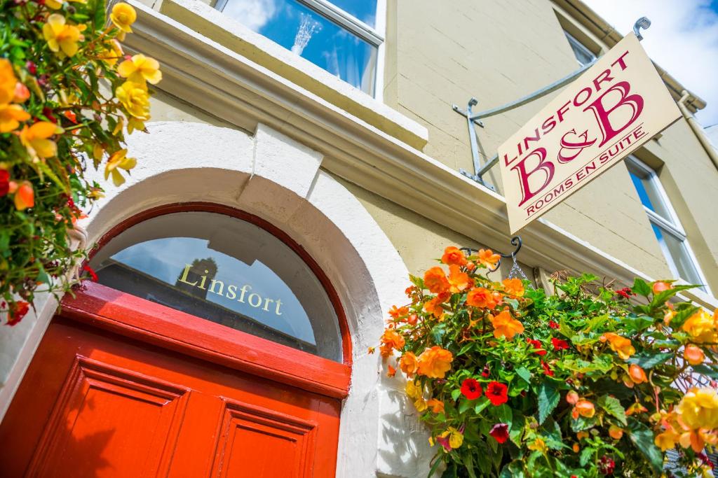una tienda con un cartel sobre una puerta roja y flores en Linsfort Guest House, en Boyle