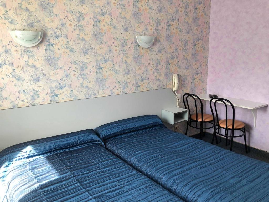 a bedroom with a bed and a table and chairs at Hôtel des Voyageurs in Saint-Chély-dʼAubrac