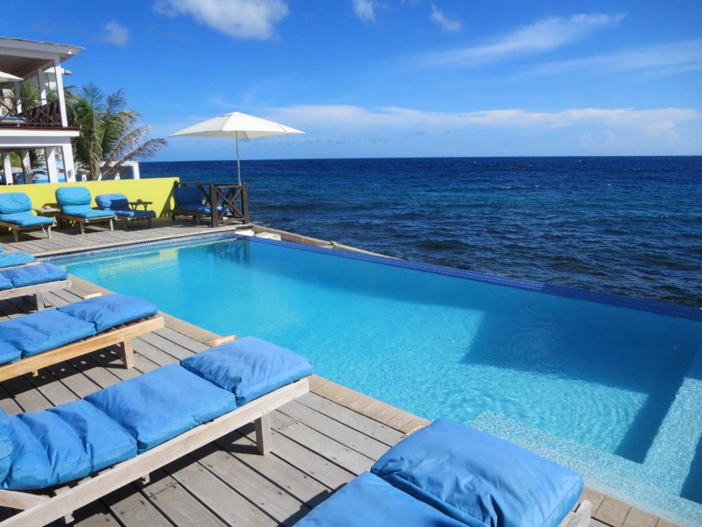 a swimming pool with chairs and the ocean at Scuba Lodge & Suites in Willemstad