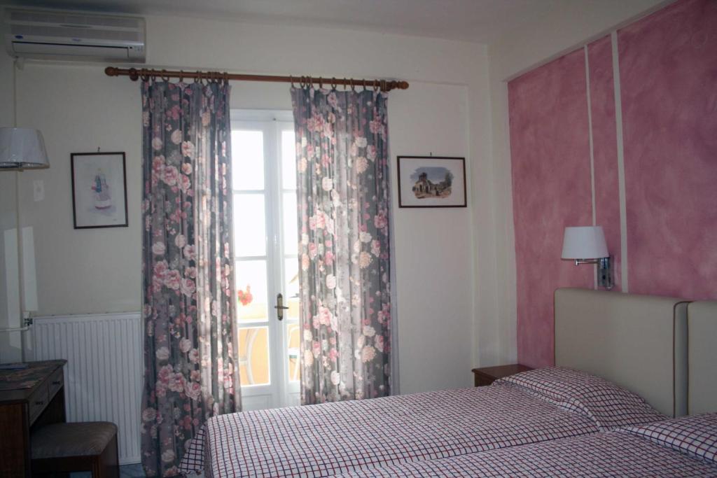a bedroom with a bed and a window with curtains at Georgia Apartments & Studios Corfu in Glyfada