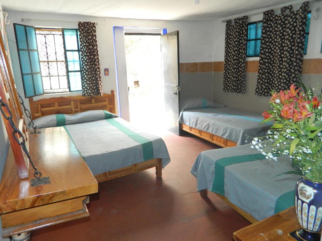 una camera con due letti e un tavolo con un vaso di fiori di Posada Joan Sebastian a Taxco de Alarcón
